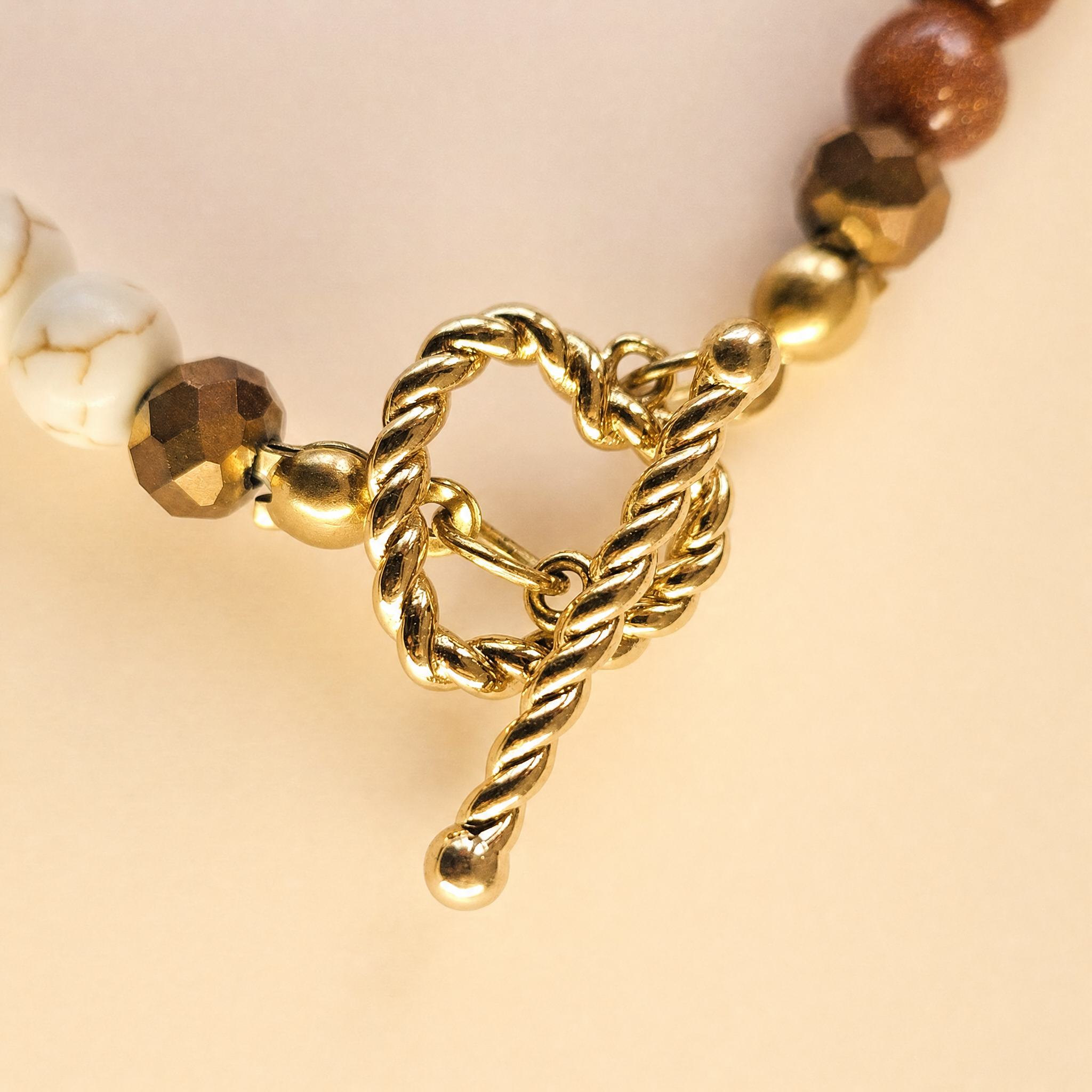 Zbliżenie na złote zapięcie toggle naszyjnika z howlitu i goldstone
